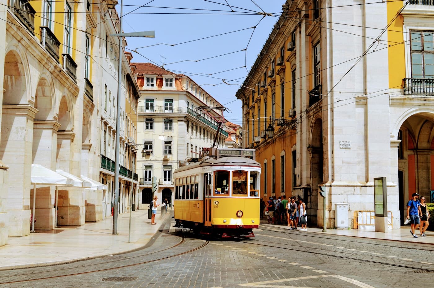 A tram crossing a bright Lisbon street
