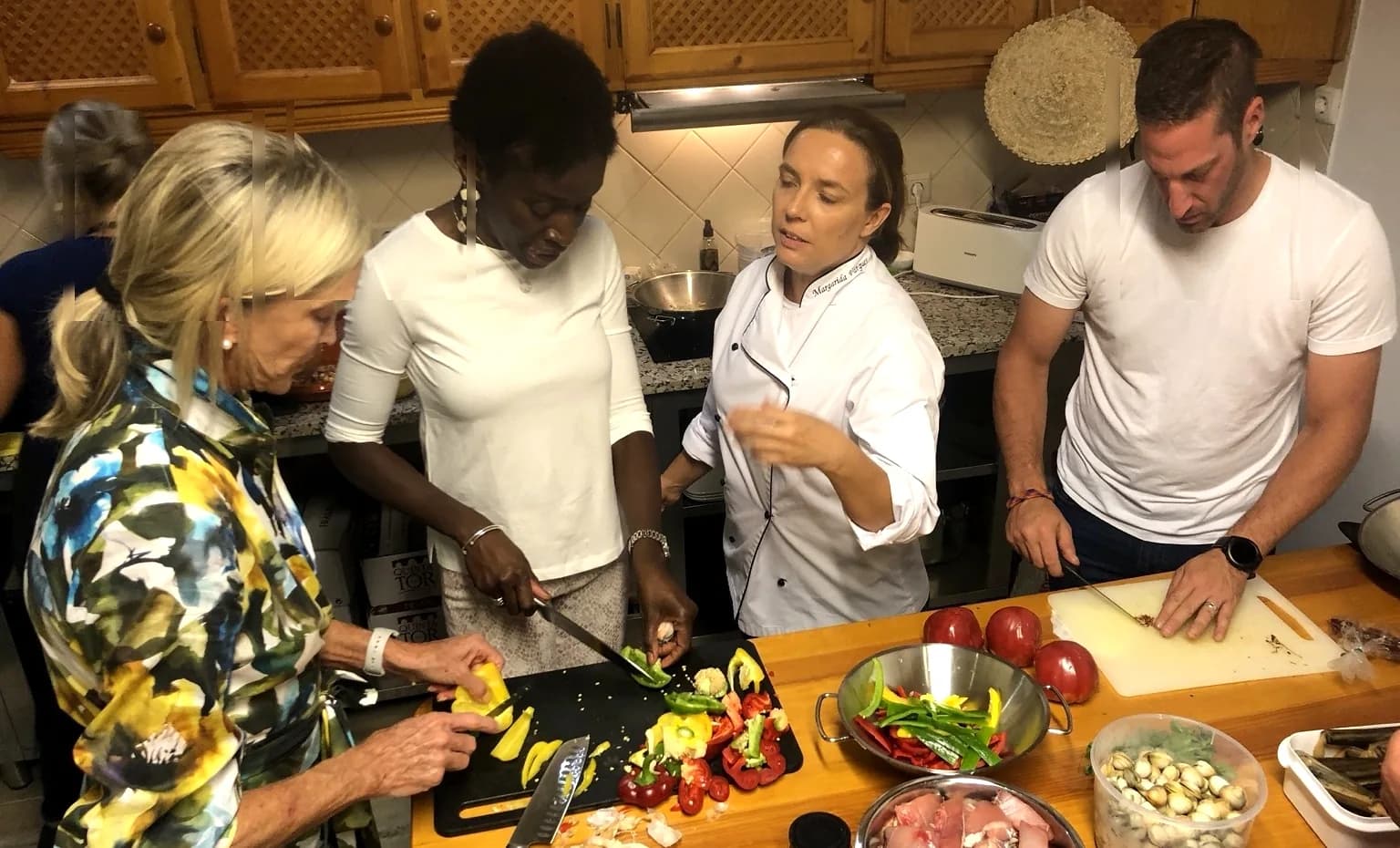 A small group cooking together around a kitchen counter with the chef